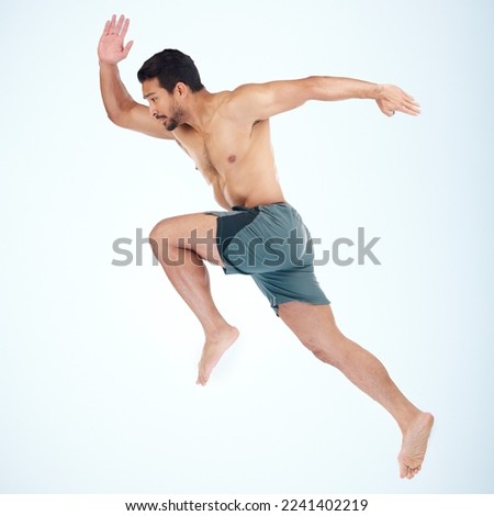 Running, jump and fitness of man in studio isolated on a blue background mock up. Sports, training and male model, athlete or runner jumping, sprint workout and exercising for health and wellness. Royalty-Free Stock Photo #2241402219