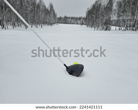 Golf club and golf ball in winter on snow on golf course. Playing golf in winter