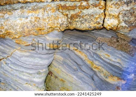 These marine sediments were lain down in a warm marine environment in the Jurassic era. The underlying grey mudstones sit as an unconformity with overlaying shallower habitat and later sandstones Royalty-Free Stock Photo #2241425249
