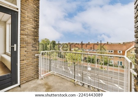 a balcony with a view of the street and houses in the distance, taken from an apartment window looking out onto the street Royalty-Free Stock Photo #2241443089