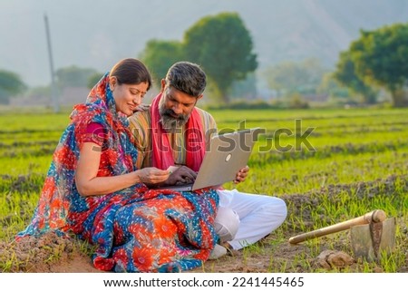 Indian farmer couple use laptop and bank card at agriculture field. Royalty-Free Stock Photo #2241445465