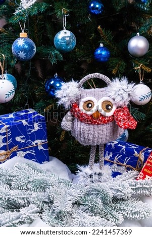 Soft plush toy owl with headphones and knitted scarf. Winter children's gift . Funny knitted red and white toy owl in a red hat and with big eyes