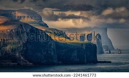 Rising and Kellingin.
This photo was taken in Kalsoy Island, Faroe islands. This picture shows the view to the west, with island  Eysturoy and the two rock formations, stacks Risin Kellingin.