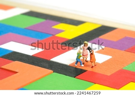 Miniature people toy figure photography. Fun learning concept. Kids play together above Montessori wooden puzzle. Isolated on white background. Image photo