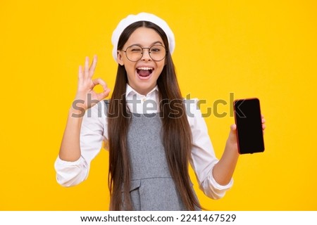 Portrait of cute teenage girl using mobile phone, chatting on web, typing sms message. Mobile app for smartphone. Kid showing blank screen mobile phone, mockup copyspace.