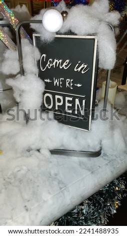 Sign board with the words come in, we are open. Decorated with white cotton.