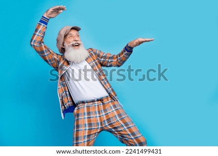 Photo of excited cheerful man pensioner wear checkered costume having fun looking empty space isolated blue color background