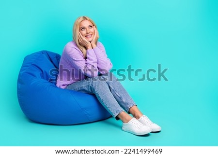 Full body photo of lovely sweet person sit comfy bag hands touch cheeks look empty space isolated on turquoise color background