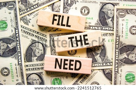 Fill the need symbol. Concept words Fill the need on wooden blocks on a beautiful background from dollar bills. Business, finacial and fill the need concept. Copy space.