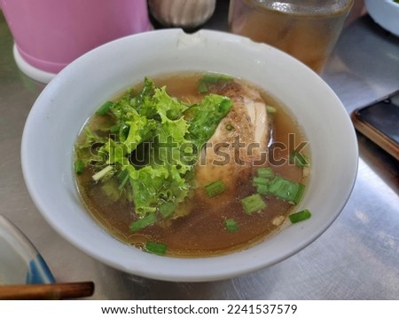 Chicken stewed in rich broth in a white porcelain bowl.