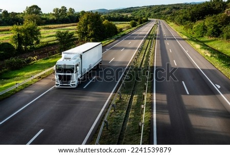 White truck driving on the highway winding through forested landscape in autumn colors at sunset Royalty-Free Stock Photo #2241539879