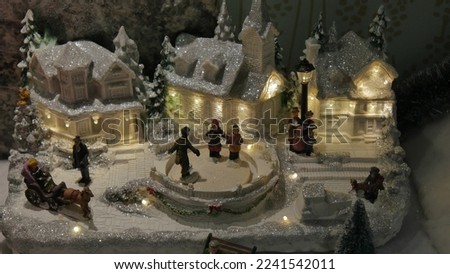 A small miniature Christmas village, with snow, figurines or people, artisan houses, ski resort, ice rink, craft decoration, model, fir trees and festive atmosphere, attraction and fun