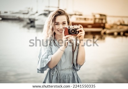 Portrait of a cute female tourist with a camera on the background of the yacht club