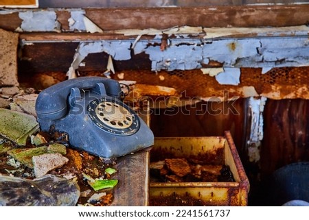 Vintage rotary phone on abandoned desk in detail with decayed wall