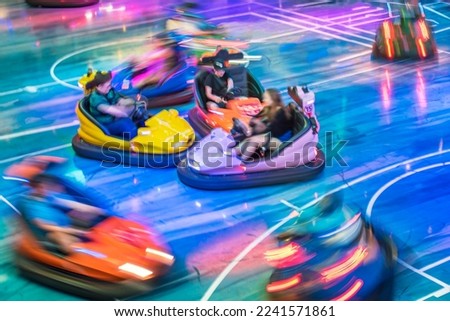 Young people are driving bumper cars in a amusement park.