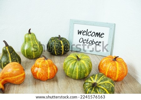 Welcome October typography text with pumpkin decoration on wooden table