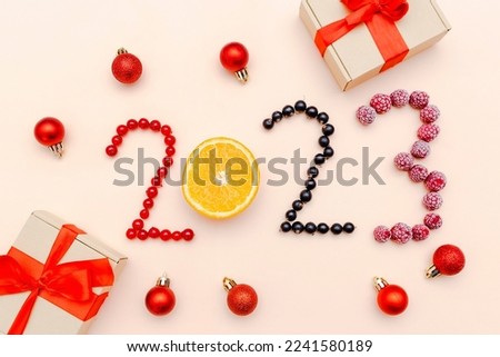 Countdown to New Year.2023 lettering number shaped with sweet fresh raspberry, currant,berry on pink background.Christmas xmas food with new year decorations close up, top view, flat lay.
