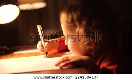 Little baby girl draws something in the evening