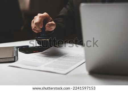 businessman hand stamping approved on certificate document contract in office. Lawyer stamping permit on paperwork at wooden desk.
