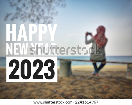 concept blurred image women taking picture and setting at the beach and word - HAPPY NEW YEAR 2023 with selective focus.  