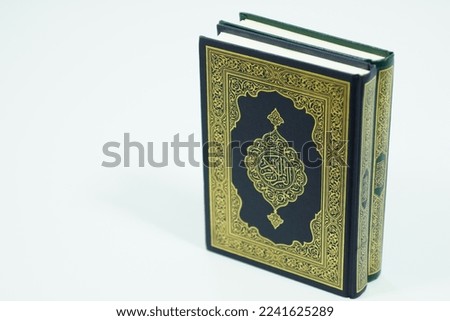 Muslim holy book with isolated background. Translation of cover text "The Quran" written in Arabic calligraphy