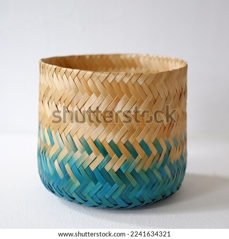 Natural cylinder bamboo basket craft coloring with splash of blue turquoise color. Woven bamboo handy craft isolated on white background. Royalty-Free Stock Photo #2241634321