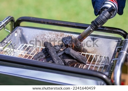 Ignite charcoal with a gas burner at camp Royalty-Free Stock Photo #2241640459