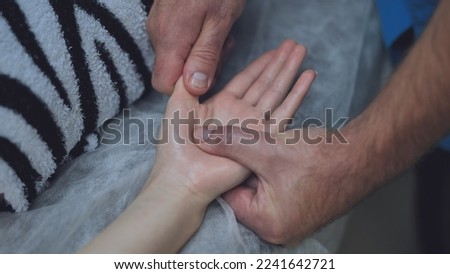 A masseur massages the wrists of a girl.