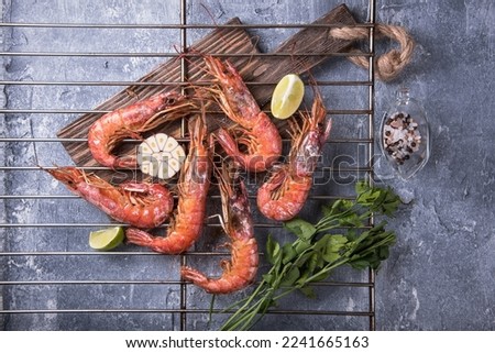 Fried langoustines on a grill grate on a marble background, top view