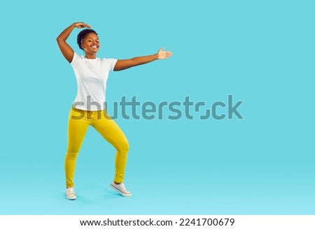 Full length portrait of funny young woman standing in martial arts pose isolated on turquoise background. African american curly girl in yellow pants and white t-shirt demonstrates fighting skills. Royalty-Free Stock Photo #2241700679