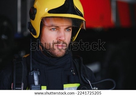 Photo of fireman with gas mask and helmet near fire engine.