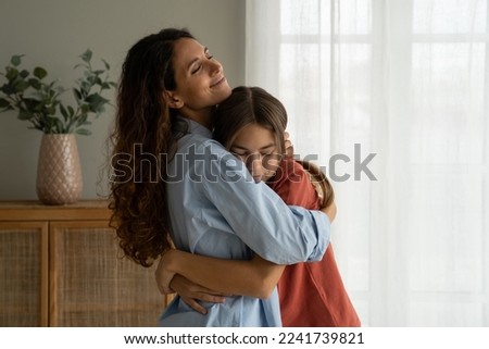 Young loving mother hugging her teenage daughter, mom demonstrating unconditional love for child, mommy cuddling supporting upset teen girl while spending time together at home. Mother-daughter bond  Royalty-Free Stock Photo #2241739821