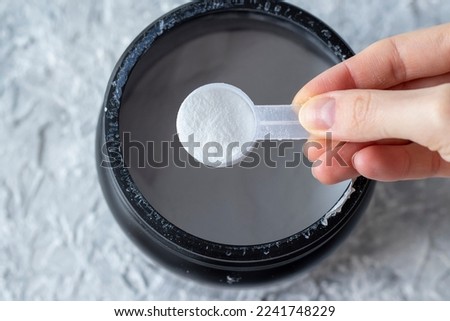 Close-up of a woman's hand with a measuring spoon of white BCAA powder. Protein shake for athletes and athletes Royalty-Free Stock Photo #2241748229