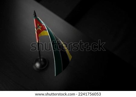 Small national flag of the Mozambique on a black background.