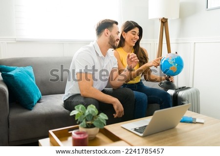 Cheerful couple at home choosing a country on the globle while planning to travel for vacations together  Royalty-Free Stock Photo #2241785457