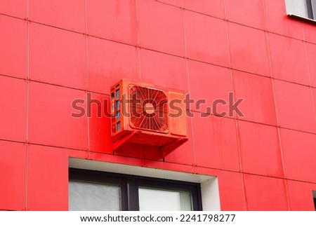 Red color air conditioner hanging on the wall of modern building in red color