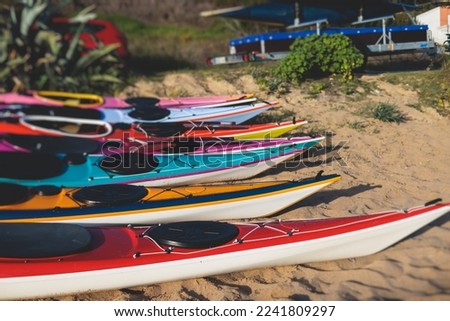 View of colourful kayaking equipment on a sandy beach, process of kayaking by the Ionian sea beach, with canoe kayak boat paddling, process of canoeing, vibrant summer picture, Greece, Corfu Island
