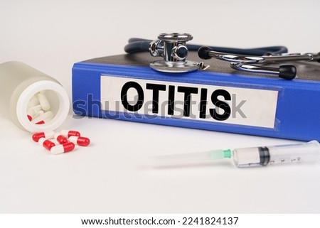 Medical concept. On a white surface there are pills, a syringe, a stethoscope and a folder with the inscription - Otitis