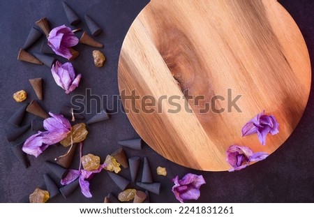 Rustic wooden mockup decorated with flowers, incense cones and frankincense on a dark background. To use as a spa design, advertisement, cover, banner or business card.
