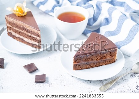 Chocolate sacher cake in a plate with cup of tea. toning. selective focus