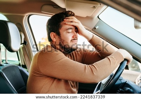 Clinging to steering wheel, closing his eyes and leaning on the drivers hand, the man is resting in the car. A common cause of accidents is fatigue at the wheel. You need to be able to rest on time. Royalty-Free Stock Photo #2241837339