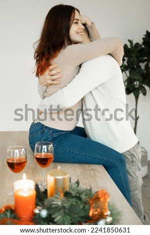 A young couple in love hugging and drinking red wine from glasses in a modern kitchen. The concept of love and tenderness.