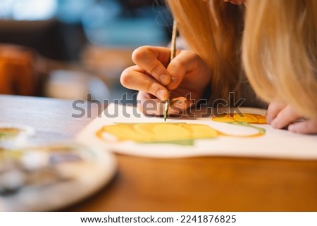 Pretty teenage girl draws a picture with poster paint. Front view of a drawing of a girl with a palette in her hand. A smiling young teenage girl draws a picture Royalty-Free Stock Photo #2241876825