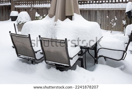 Outdoor furniture is covered with snow in a winter. Winter patio and garden during snowfall. Nobody, street photo, selective focus