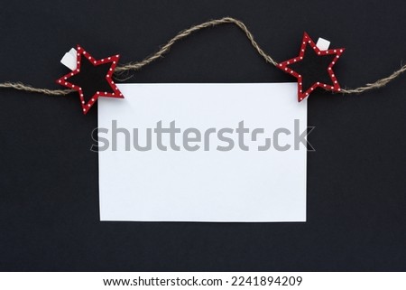 Mockup. A white sheet of notepad on a black background. A sheet on clothespins and a rope. Conceptual business minimalism. The concept of advertising, monochrome design, stylish Christmas banner