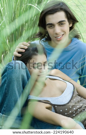 Young couple sitting in grass, woman leaning head against boyfriend's knee