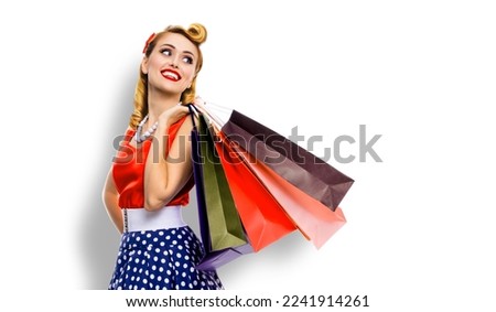 Portrait image of very happy, cheerful excited looking up woman in pinup dress holding, carrying many shopping bags, isolated on white background. Sales discounts rebates or consumer bank credit ad.