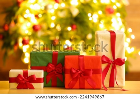 Gifts on table against blurred Christmas tree
