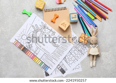 Coloring pages, felt-tip pens, pencils, notebook and toys on grunge background