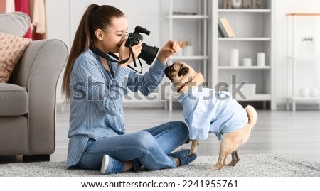 Teenage girl taking photo of cute pug dog at home